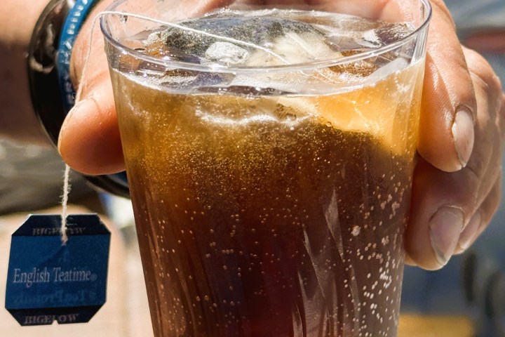 a hand holding a glass of beer on a table