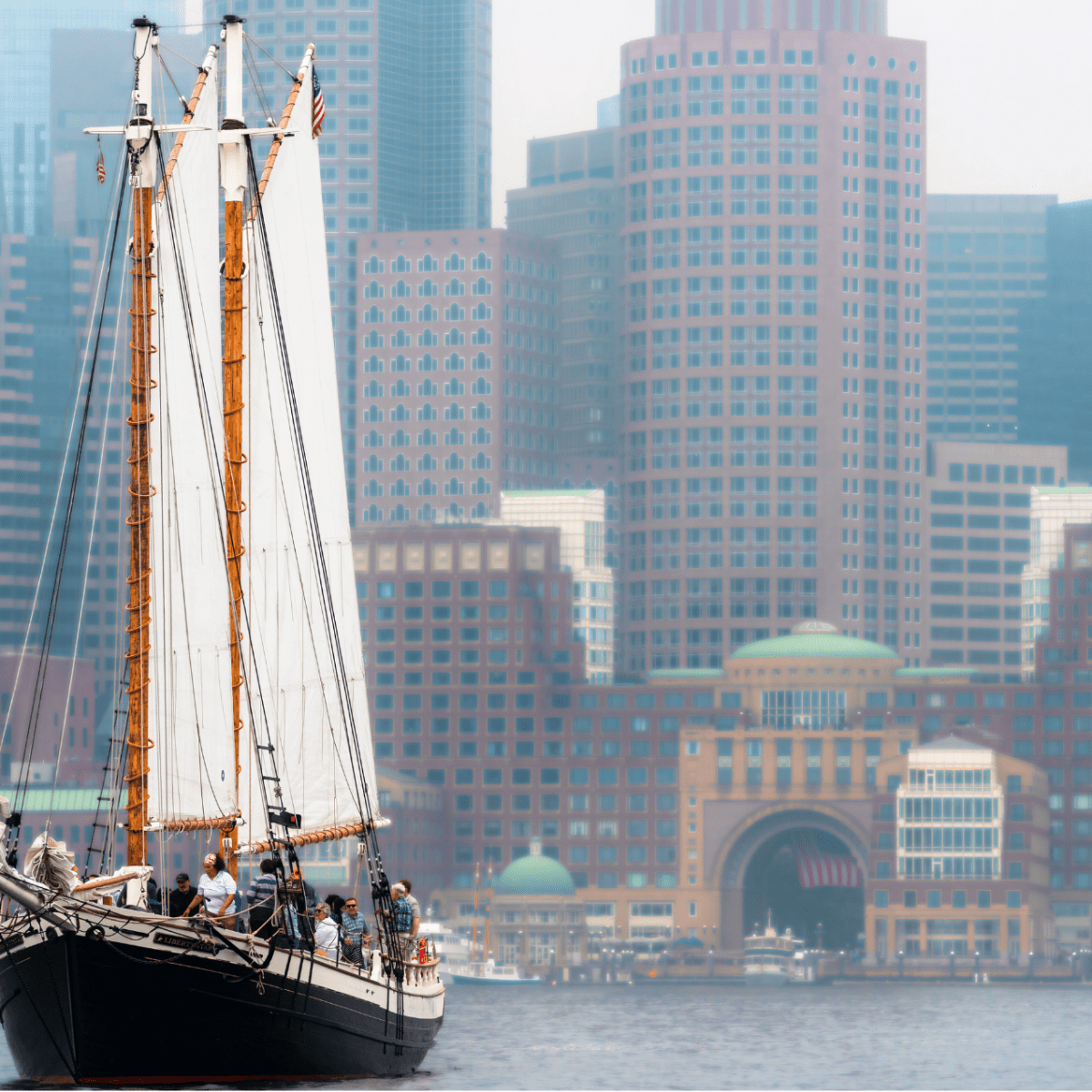 Sailing ship in harbor with modern city skyline in the background.