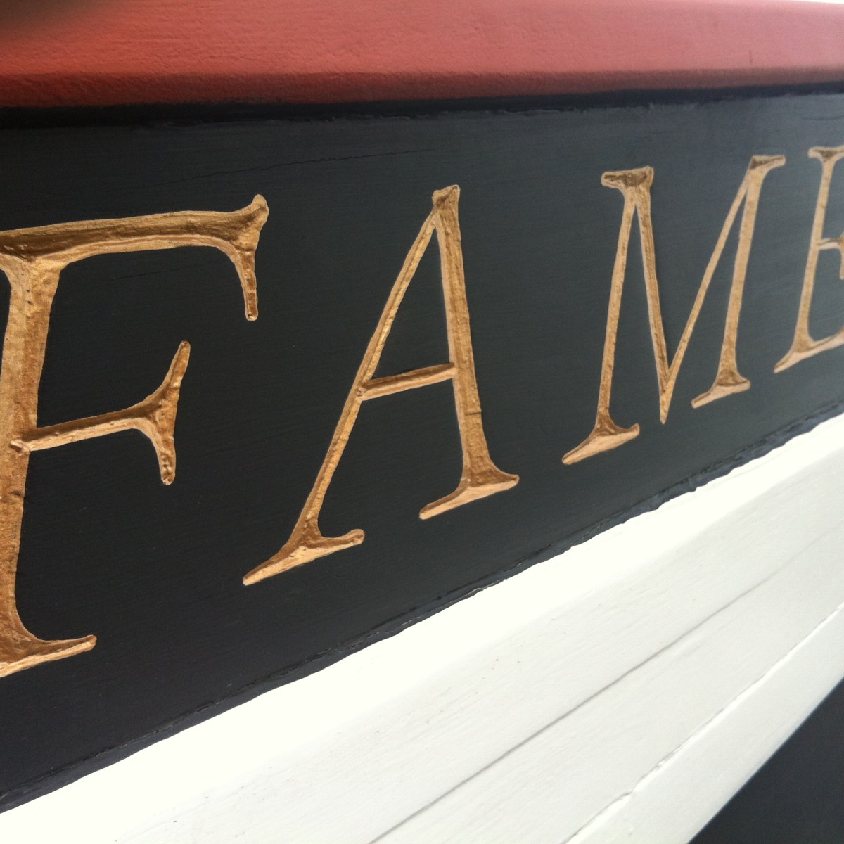 Close-up of gold lettered text 'FAME' on a black and white boat surface.
